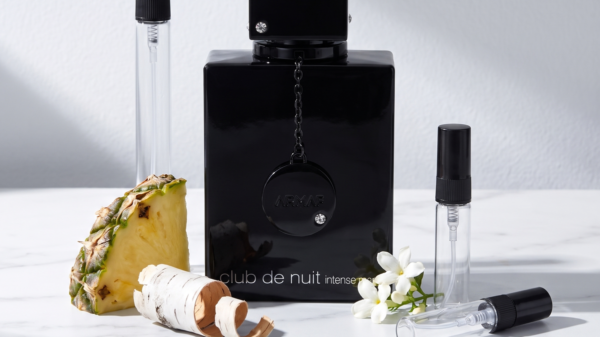 Decants de Armaf: la botella negra de Club de Nuit Intense Man junto a tres atomizadores de vidrio sobre marmol