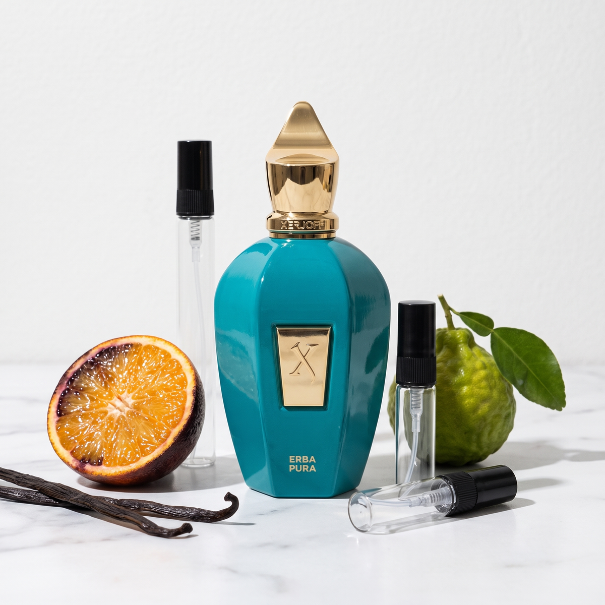 Decant de Xerjoff Erba Pura en 3, 5 y 10 ml junto a la botella turquesa original de Xerjoff con naranja sanguina, bergamota y vainas de vainilla