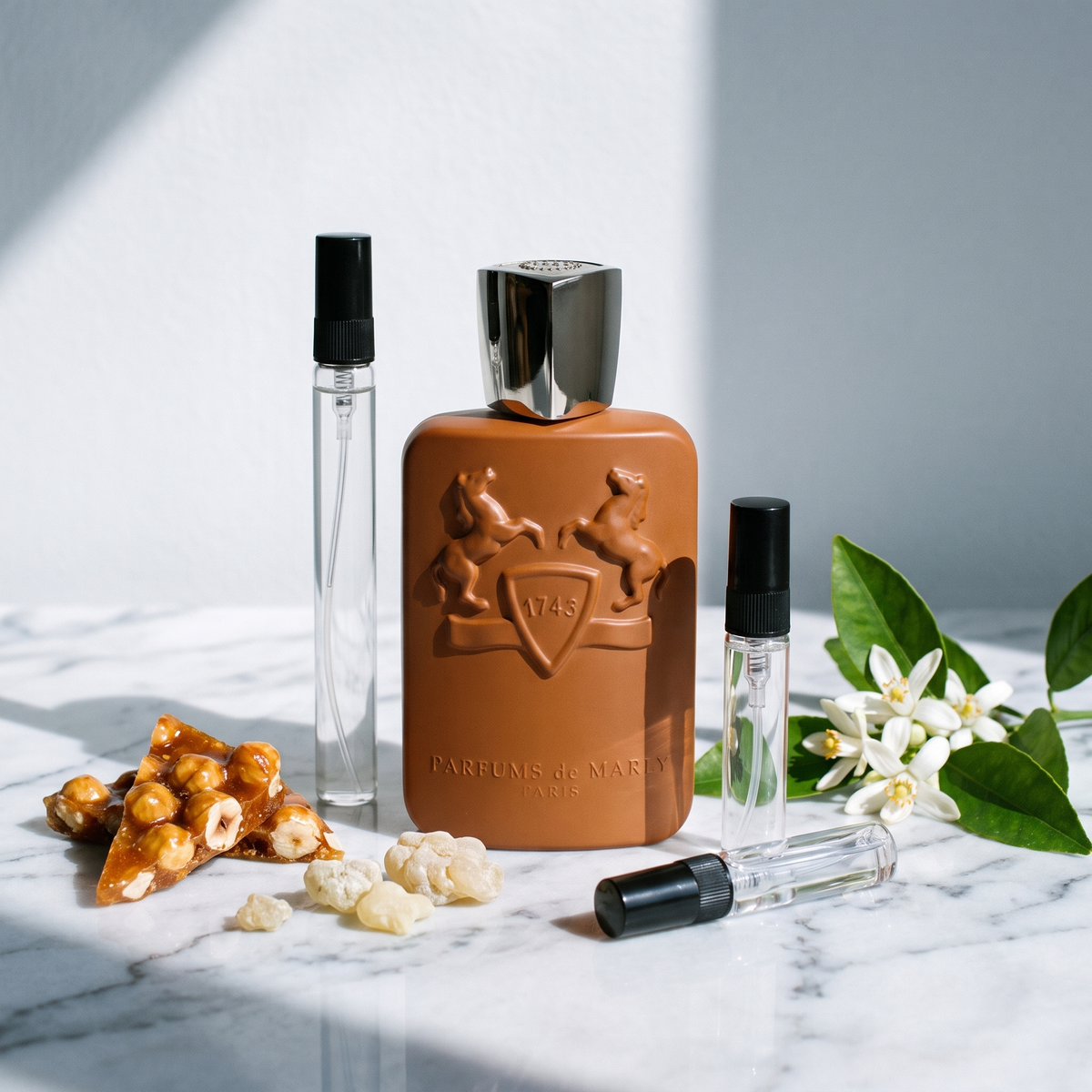 Decant de Parfums de Marly Althaïr en 3, 5 y 10 ml junto a la botella caramelo original de Parfums de Marly con praliné de avellanas, resina de elemí y flor de azahar