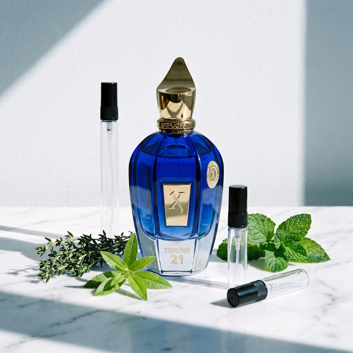 Decant de Xerjoff Torino21 en 3, 5 y 10 ml junto a la botella azul degradada original de Xerjoff con tomillo, verbena de limón y hojas de menta