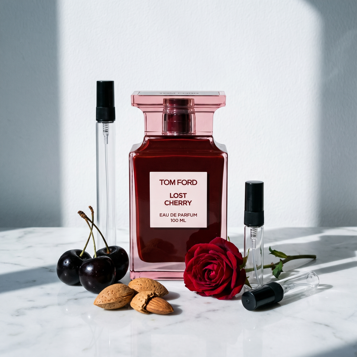 Decant de Tom Ford Lost Cherry en 3, 5 y 10 ml junto a la botella roja original de Tom Ford con guindas negras, almendras y una rosa roja