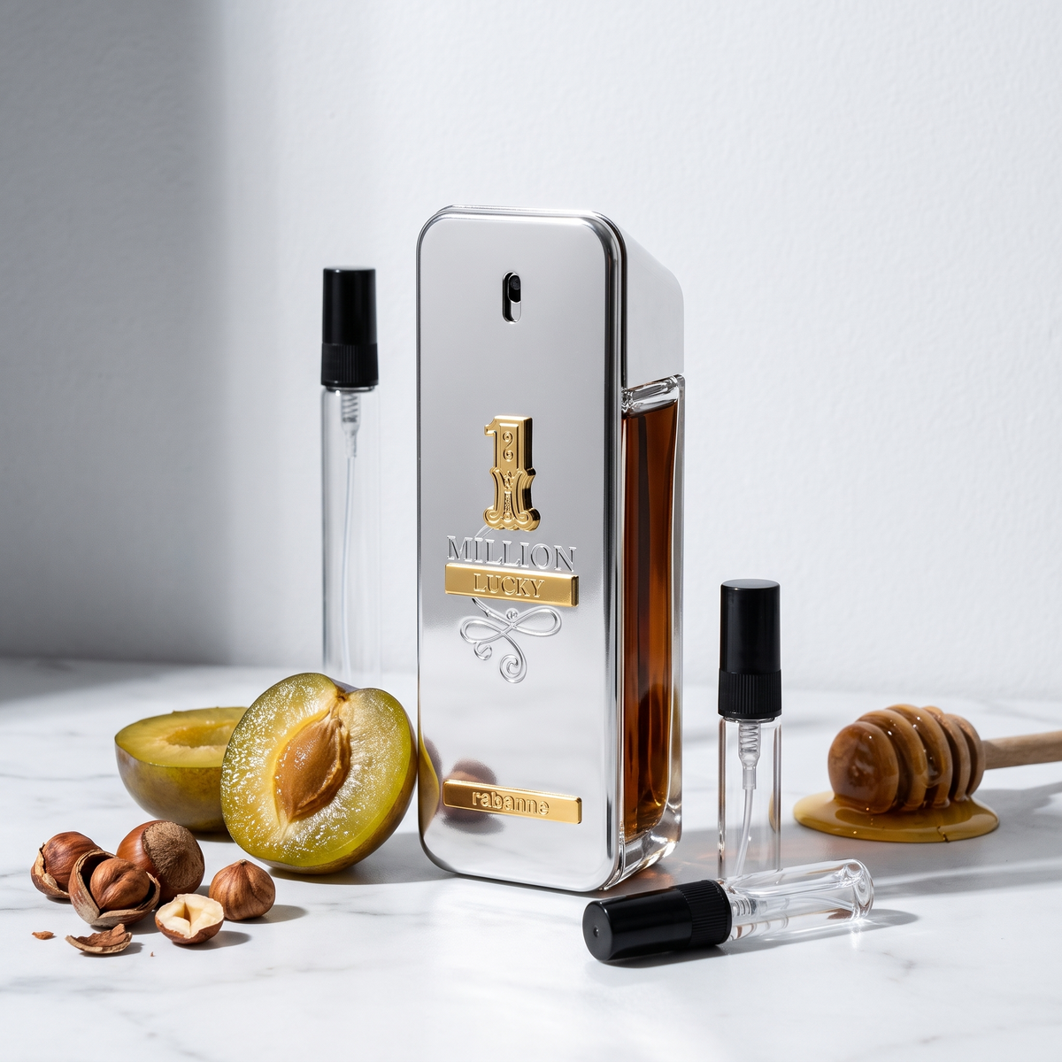 Decant de Paco Rabanne 1 Million Lucky en 3, 5 y 10 ml junto a la botella lingote plateada original de Paco Rabanne con una ciruela partida, avellanas tostadas y miel